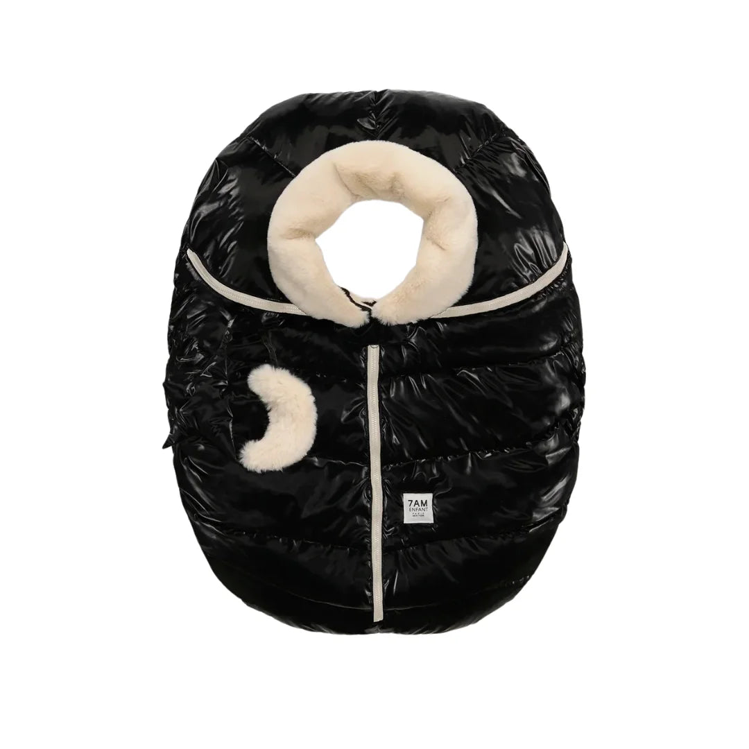 A flat-lay view of the 7AM Enfant car seat cocoon in black liquid shine and arctic white faux fur.