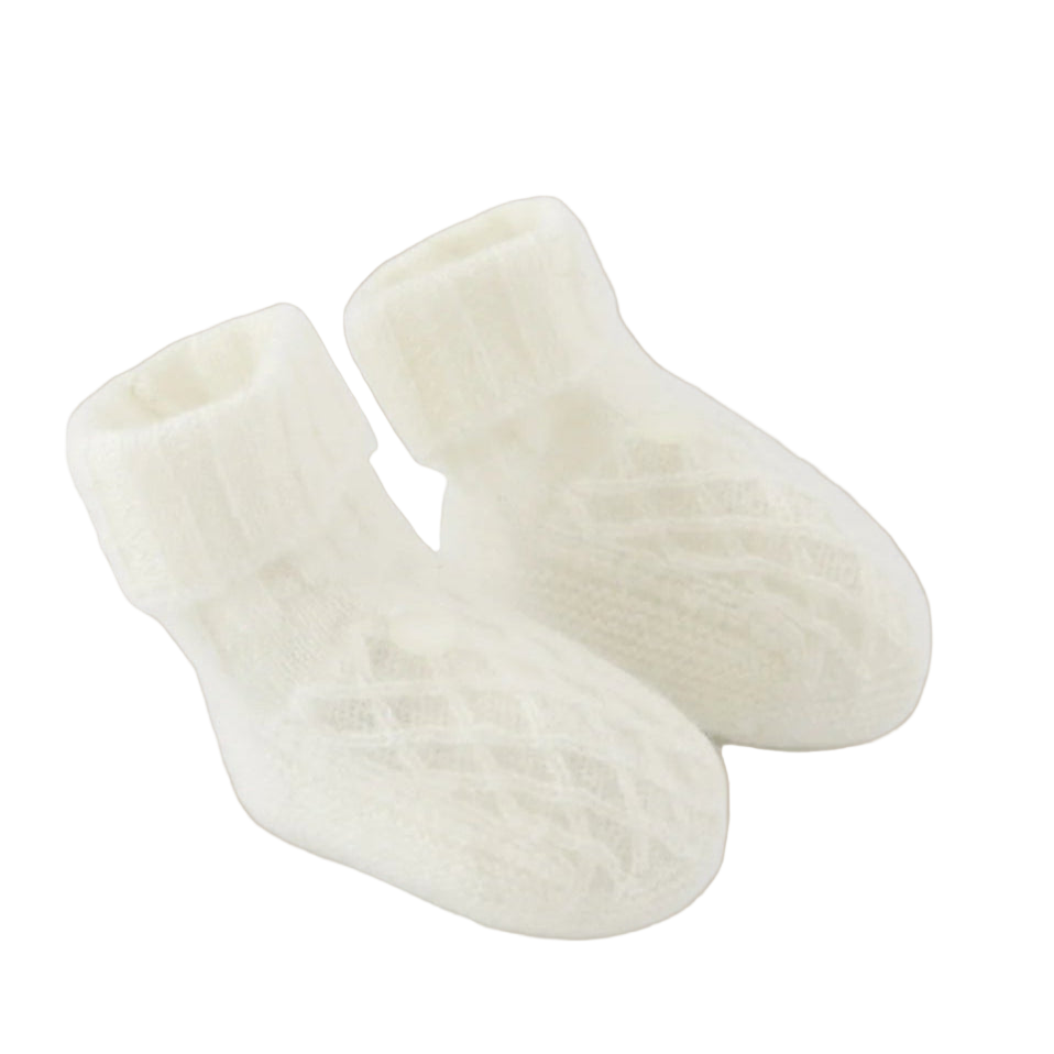 Pair of white baby socks on a light beige background