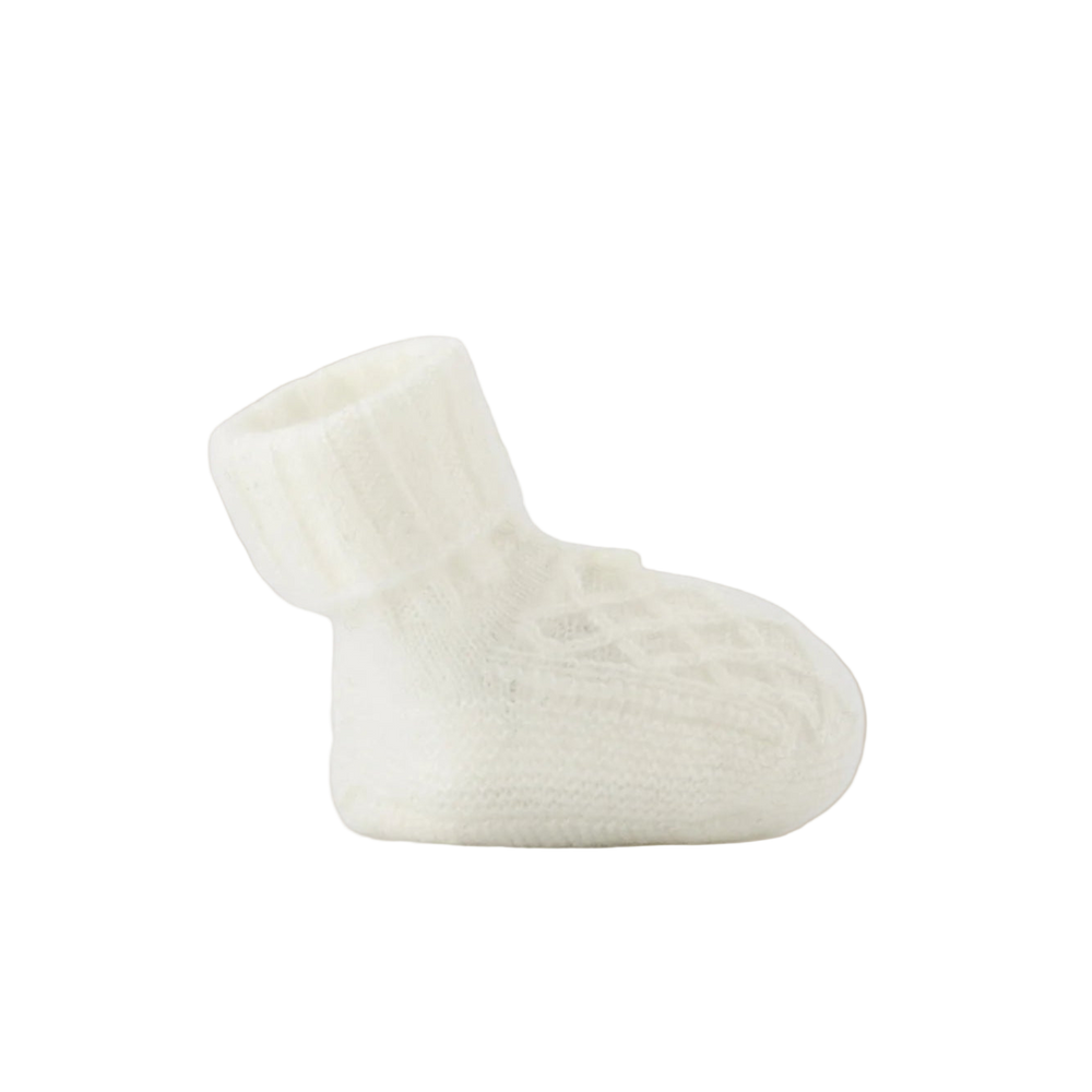 White baby bootie on a beige background