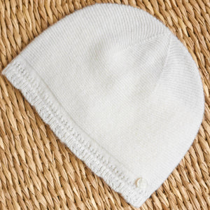 White knit beanie on a woven straw surface