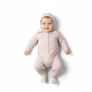 Baby in a pink onesie with a hood on a white background