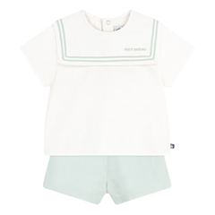 White sleeveless top with green trim and light green shorts on a white background