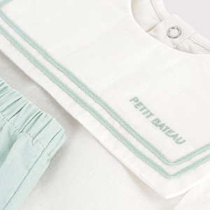 Baby outfit with mint trim and 'Petit Bateau' branding on a light background