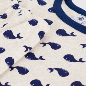 Baby outfit with navy whale pattern on a textured fabric background