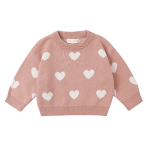 Pink sweater with white heart patterns on a white background