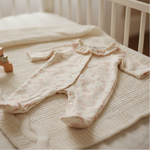 Pink baby outfit on a textured blanket in a crib