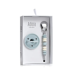 Adora baby gift set in a white box, featuring a pale pink silicone pacifier and a rose gold and cream beaded pacifier clip.