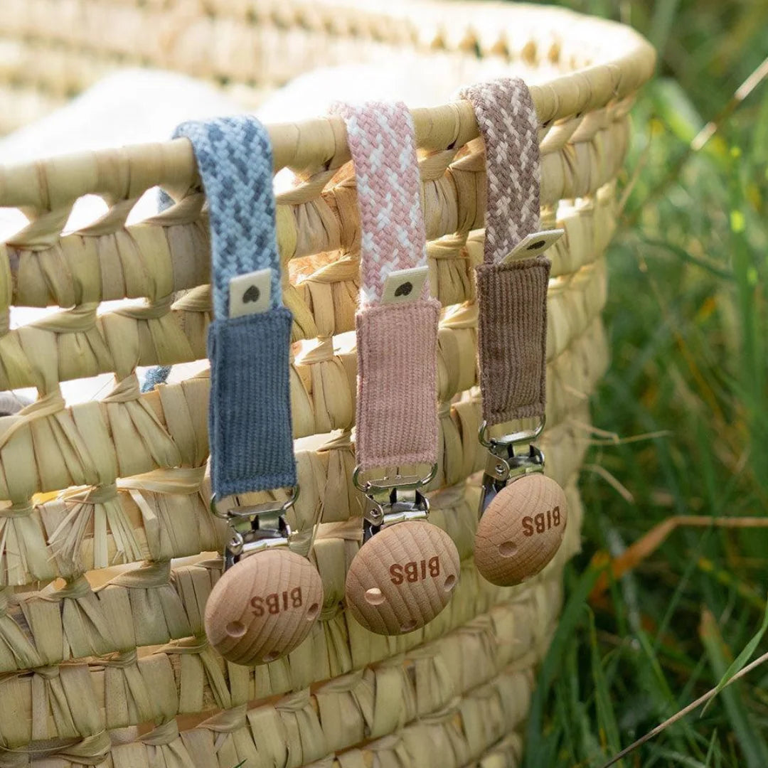 A breathtaking BIBS Braided Pacifier Clip showcasing its immaculate organic cotton weave and timeless wooden clasp.