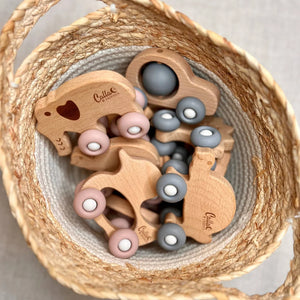 Wooden toys with gray and pink elements in a woven basket