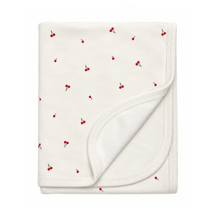 A flat-lay view of the Coton Pompom mini cherries blanket in ivory.
