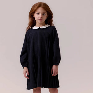 child wearing the Cottier navy dress happily during a family celebration.