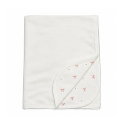 A flat-lay view of the Coton Pompom bows corduroy blanket in ivory.