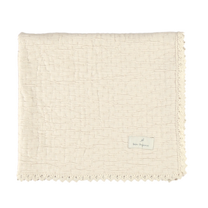 Beige textured blanket with a brand label on a white background
