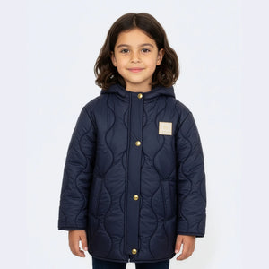 Child wearing a navy quilted jacket on a light purple background