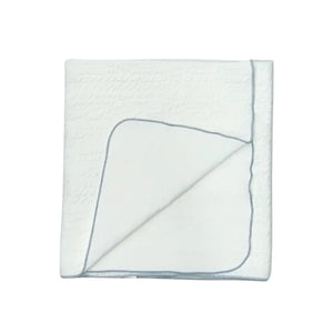 A front view of the Latte jacquard blanket in white with a blue edge.