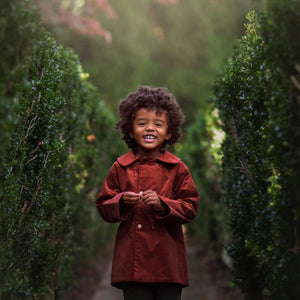 A child wearing the Lillies Dream rosewood corduroy coat happily during an outdoor outing.