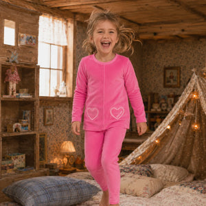 A child relaxing comfortably while wearing the Little Label hot pink pajama set.