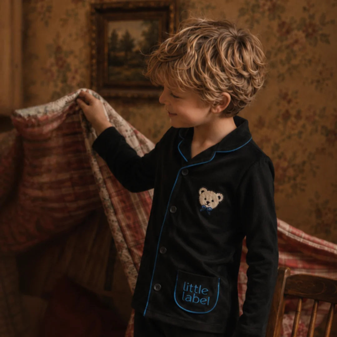 A child relaxing comfortably while wearing the Little Label luxury pajama set.