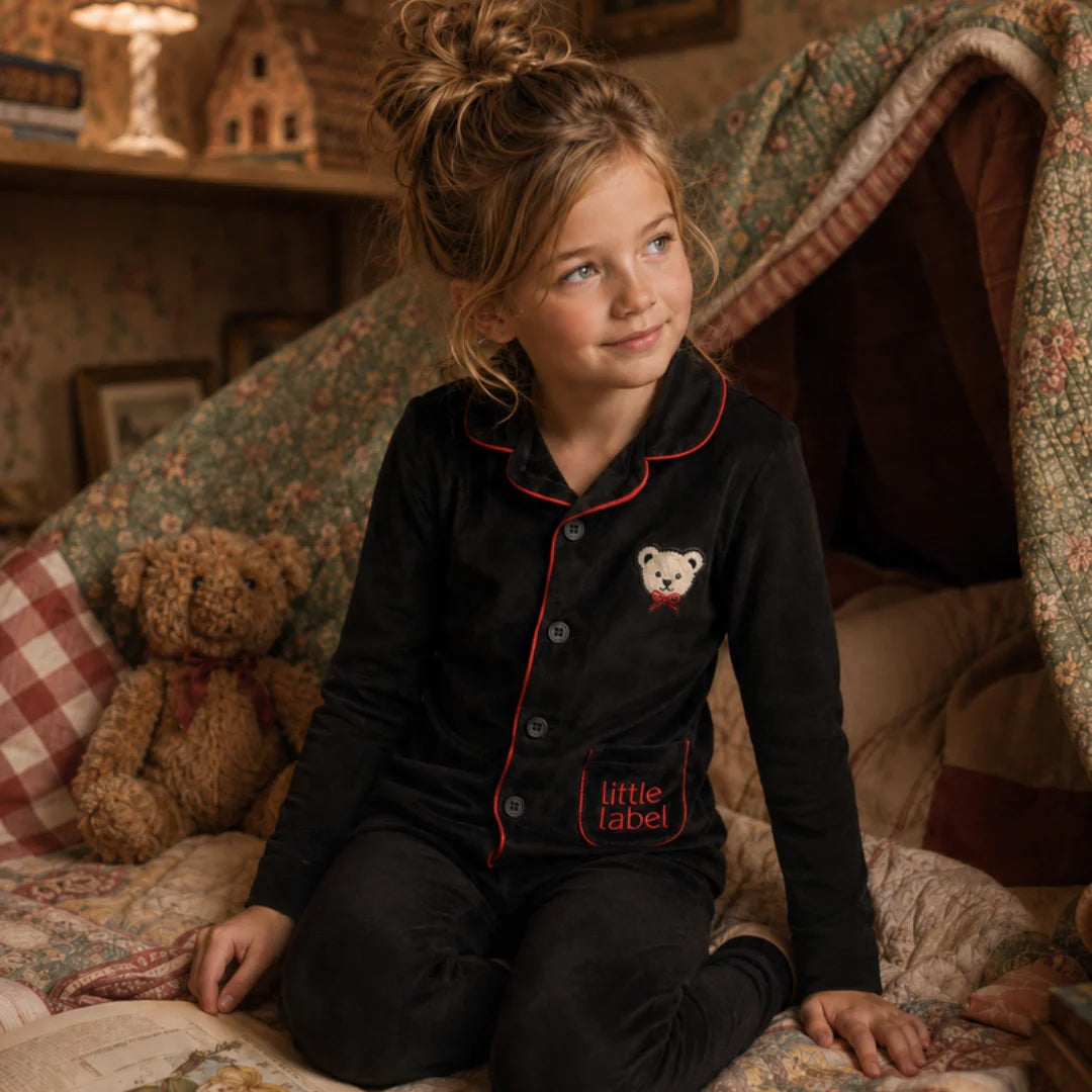 A child relaxing comfortably while wearing the Little Label holiday pajama set.