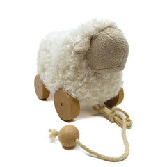 Plush sheep toy with wooden wheels and a pull string on a white background