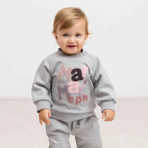 A child wearing the MarMar Copenhagen cloud grey sweatshirt comfortably during an outdoor playground outing.