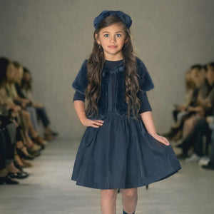 A young girl wearing the Mode Avant fur shrug and taffeta skirt set at a fashion show