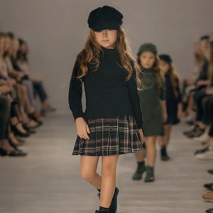 A young girl wearing the Mode Avant sweatshirt dress paired with boots during a fashion runaway.