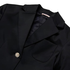 A close-up of the decorative embellished buttons and logo patch on the N°21 Kids blazer.