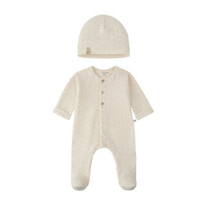 A baby sleepwear set featuring a long-sleeve footed sleeper and a matching beanie hat, both in a warm cream color with tiny light brown polka dots. The sleeper has three front buttons and a small fabric brand tag on the inside neck.