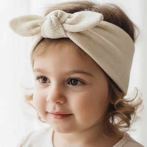Child wearing a beige headband with a bow on a white background