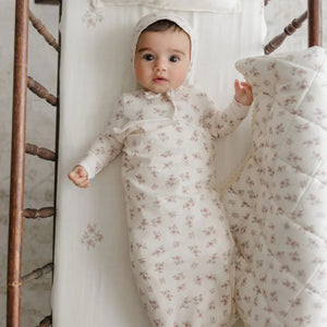 A newborn infant securely swaddled in the Peluche Bebe blossom blanket during a portrait session.