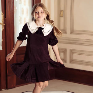 A child styled in the Pompomme cocoa shirt dress during a family celebration.
