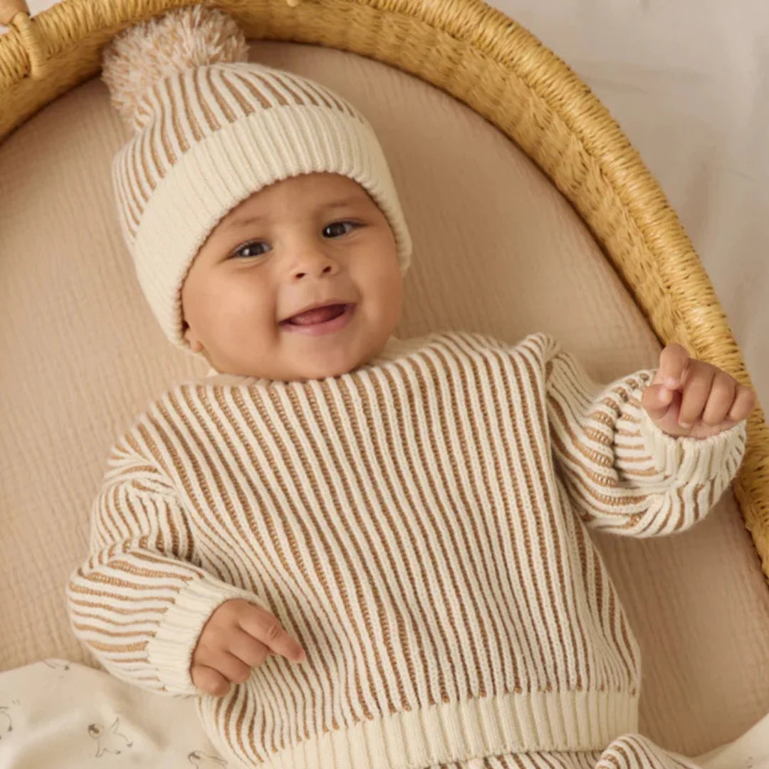 A baby boy smilling comfortably while wearing the gold relaxed knit sweater by Quincy Mae.