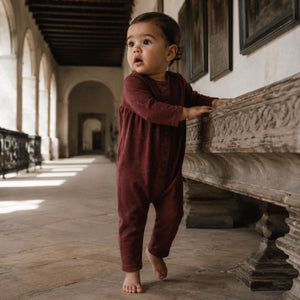 A happy baby wearing the cozy burgundy RetroKid Isla romper.