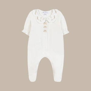 White baby romper with ruffled collar on a beige background