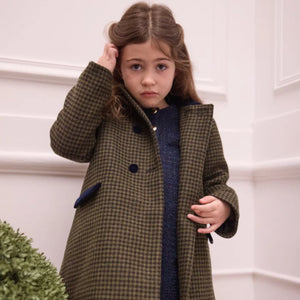 A child styled in the Tartine et Chocolat houndstooth coat during an outdoor winter outing.
