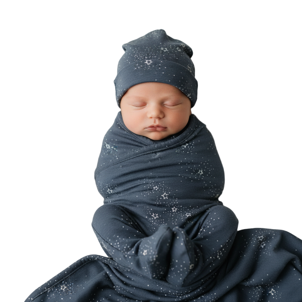Newborn baby swaddled in a dark blue blanket with star patterns, wearing a matching hat.