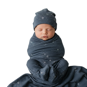 Newborn baby swaddled in a dark blue blanket with star patterns, wearing a matching hat.