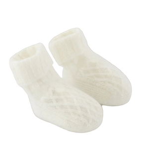 Pair of white baby socks on a light beige background