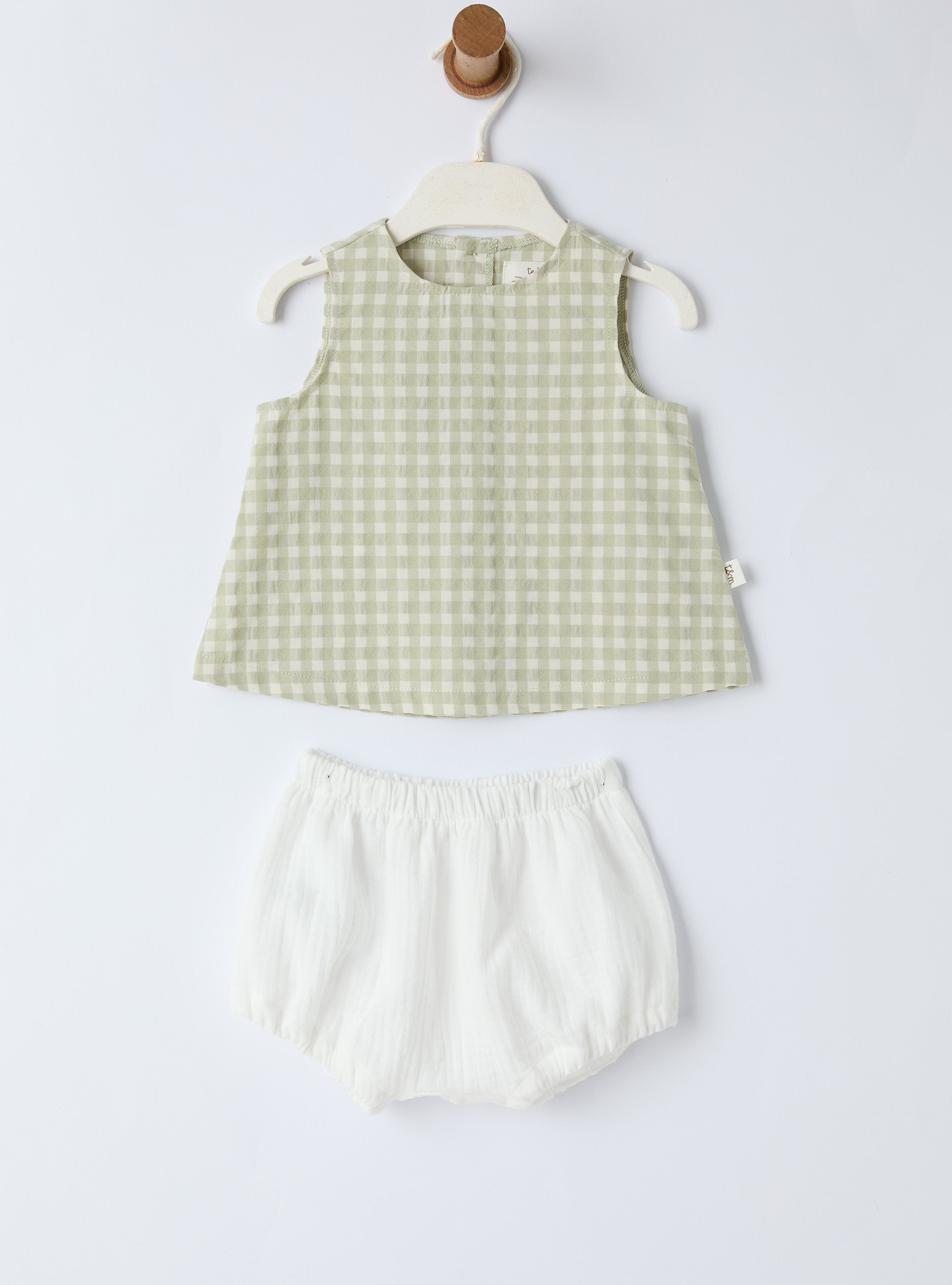 Green checkered sleeveless top and white shorts set on a white background
