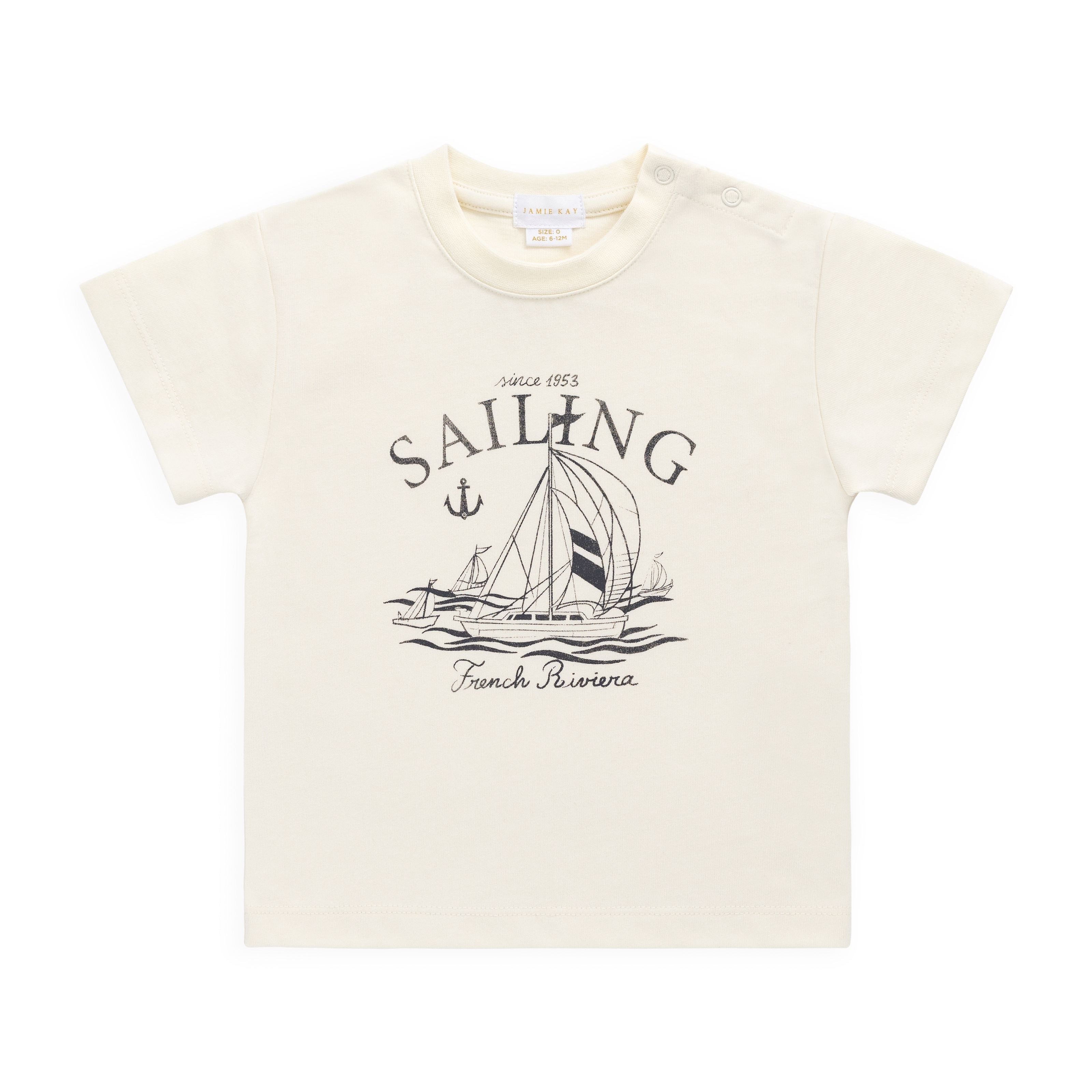 Beige t-shirt with sailing graphic and text on a white background