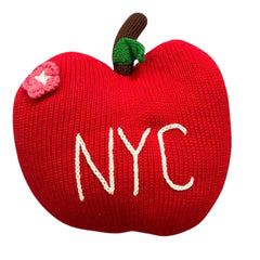 Red knitted apple-shaped pillow with 'NYC' embroidery on a white background