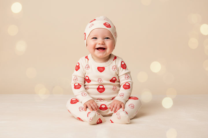 Baby onesie with red patterns on a wooden floor