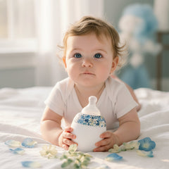 White baby bottle with floral patterned cover on a white background
