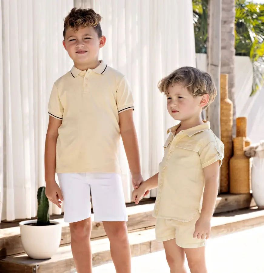Two children wearing matching yellow outfits standing outdoors.
