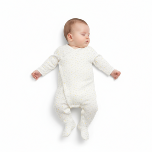 Baby in a white textured onesie lying on a white background