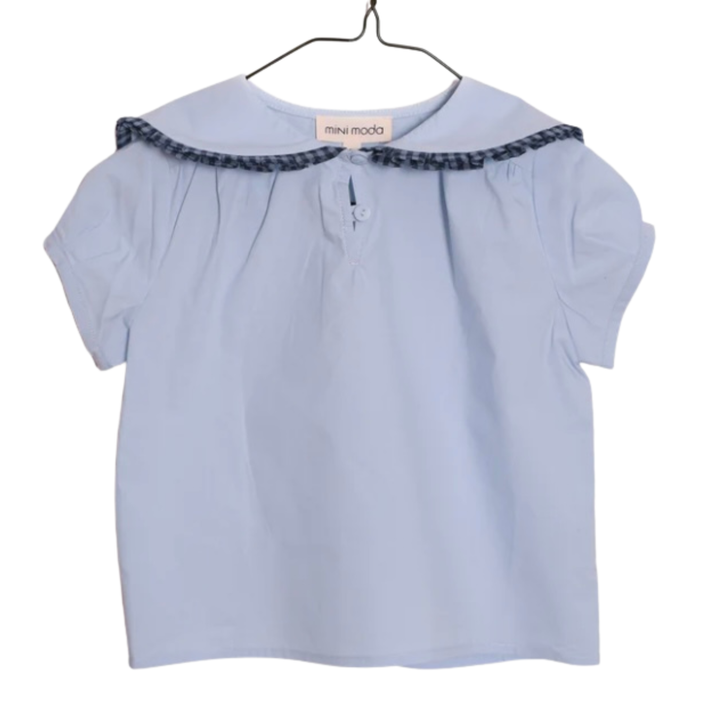 Light blue blouse with black trim on a hanger against a white background