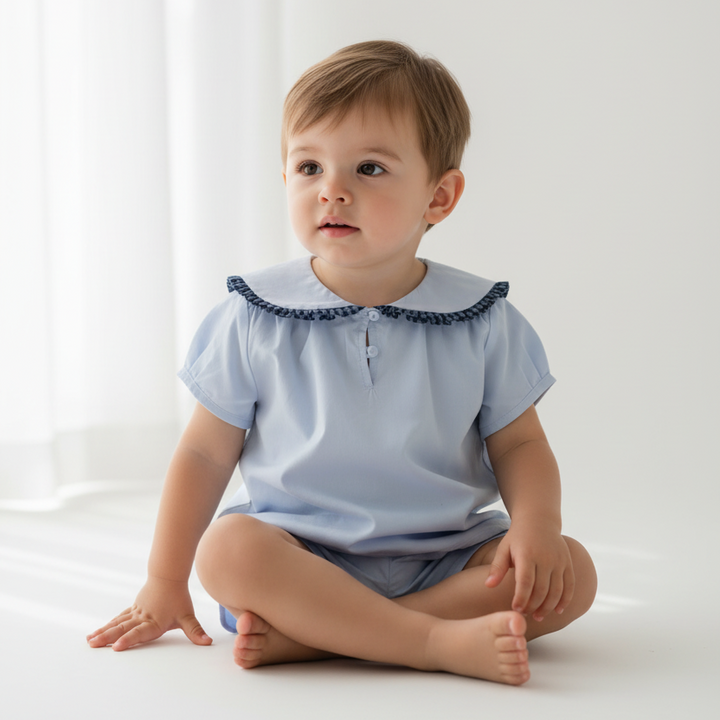Child wearing a light blue shirt with a collar on a white background