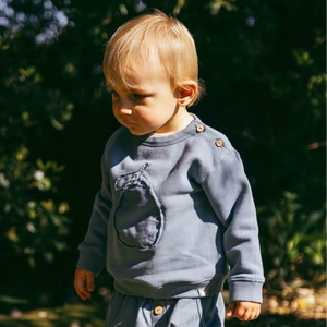 Child wearing a blue outfit with a graphic design outdoors