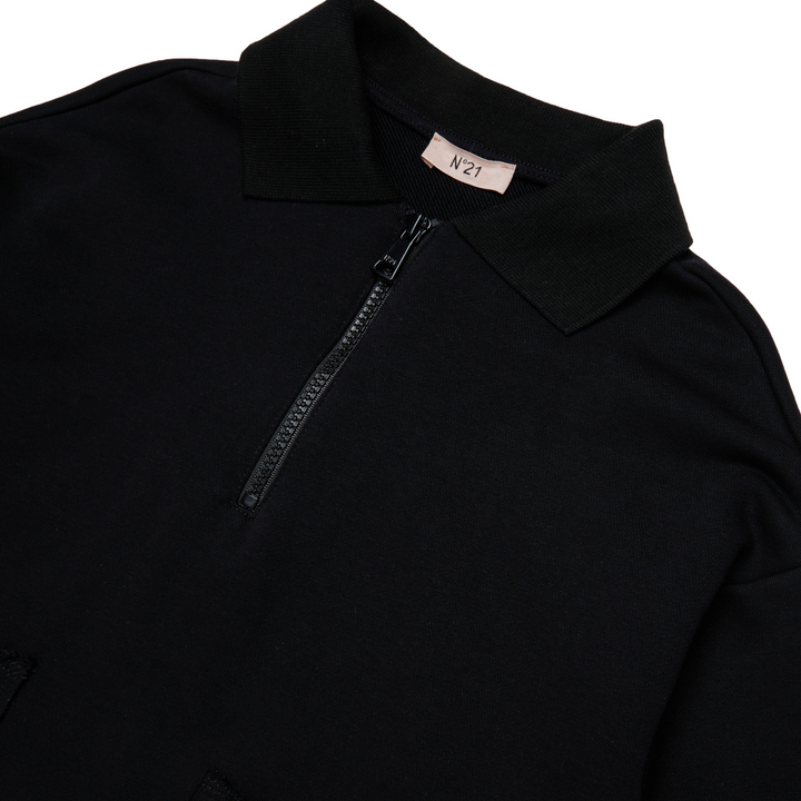 Close-up of a black garment with a zipper and label on a white background